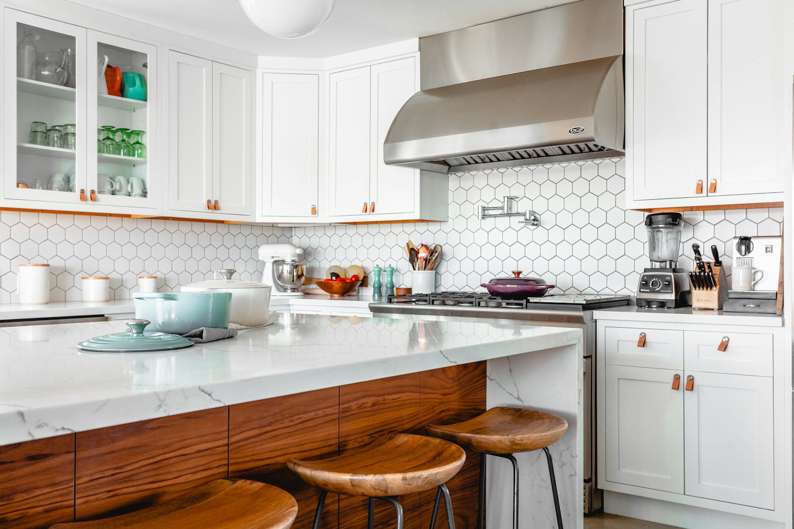 Open-concept kitchen with white marble waterfall island, barstools, and stainless range hood in Del Mar.